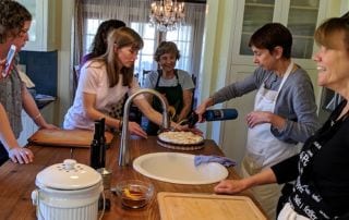 Photo of French students and teacher gathered around in kitchen learning how to use torch