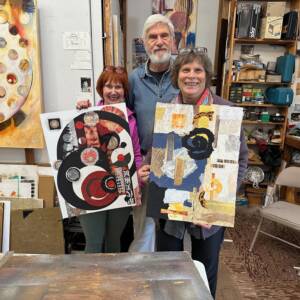 Three people standing in an art studio holding up their collage art